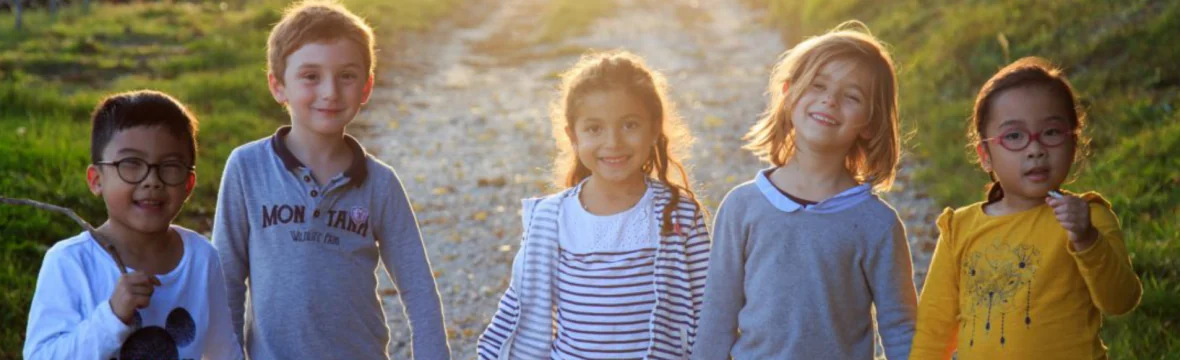 Cuatro niños sonríen en un camino con la luz del atardecer