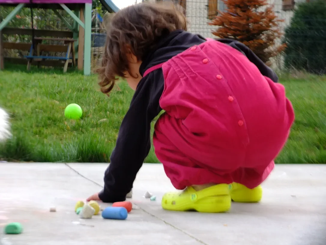 Un niño dibuja con tiza en el suelo del patio