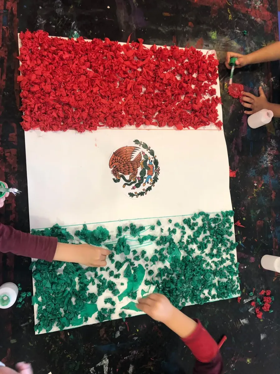 Manos de niños pegan confeti para hacer una bandera
